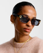 Woman wearing katie loxton malibu tortoiseshell sunglasses with a neutral background