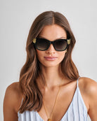Woman wearing katie loxton seychelles sunglasses with gold frames on a plain background