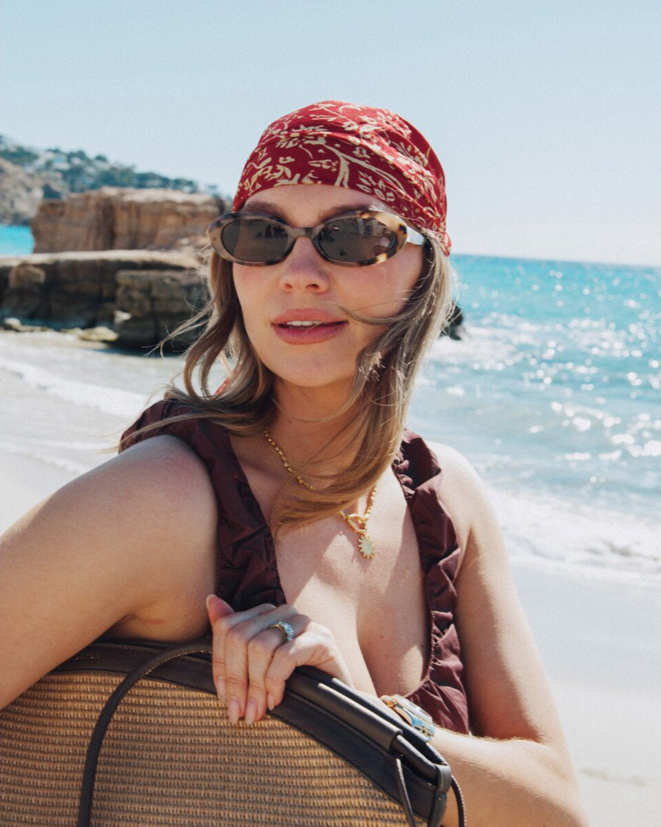 Woman with a red bandana and sunglasses on a beach