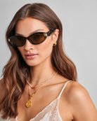 Woman wearing katie loxton sunglasses with a neutral background