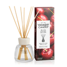 Yankee Candle Black Cherry reed diffuser with natural reed sticks in a clear glass bottle, shown next to its retail box featuring a glossy red cherry design.