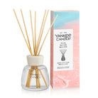Yankee Candle Pink Sands reed diffuser bottle with natural wood reeds and its retail box on a white background.