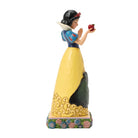 Statue of snow white character in a yellow dress holding an apple on a white background