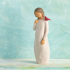 willow tree messenger figurine of a woman with a red bird on her shoulder in a light blue background