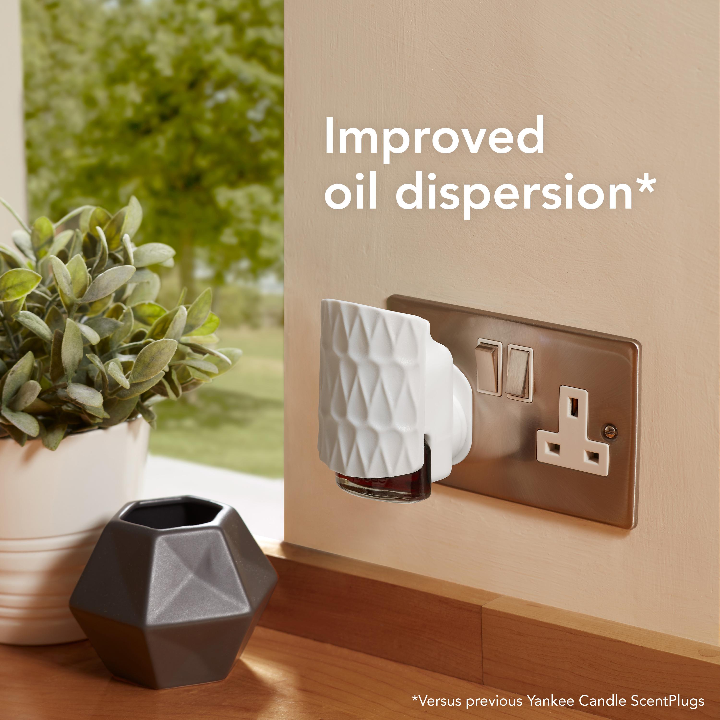 Yankee Candle ScentPlug on a wall socket with decorative elements and text about improved oil dispersion.
